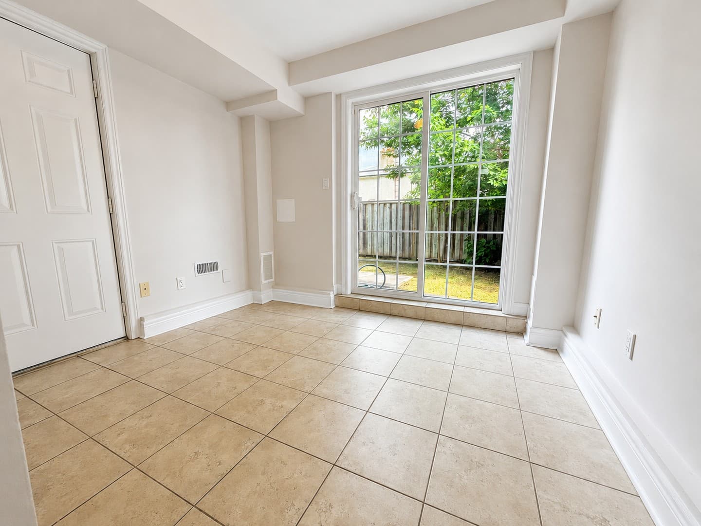 Finished empty basement recreation room with sliding doors